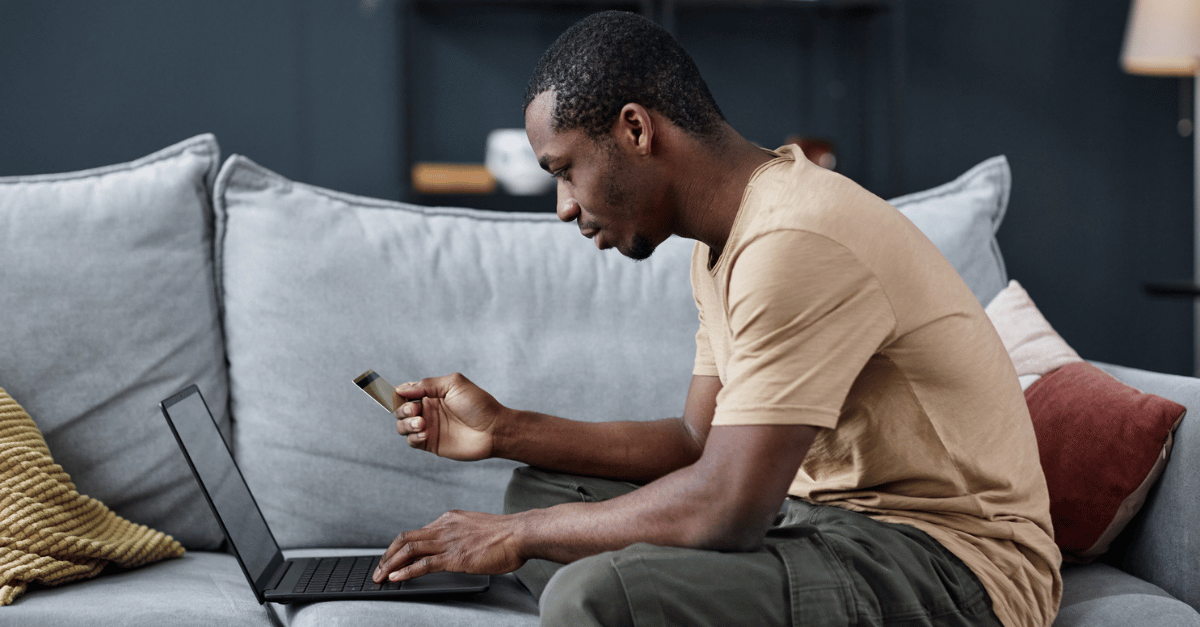 Man sitting in his living room shopping online with his credit card in hand