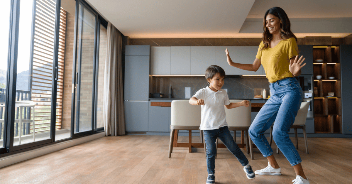 Mother and son laughing and dancing in their new living room