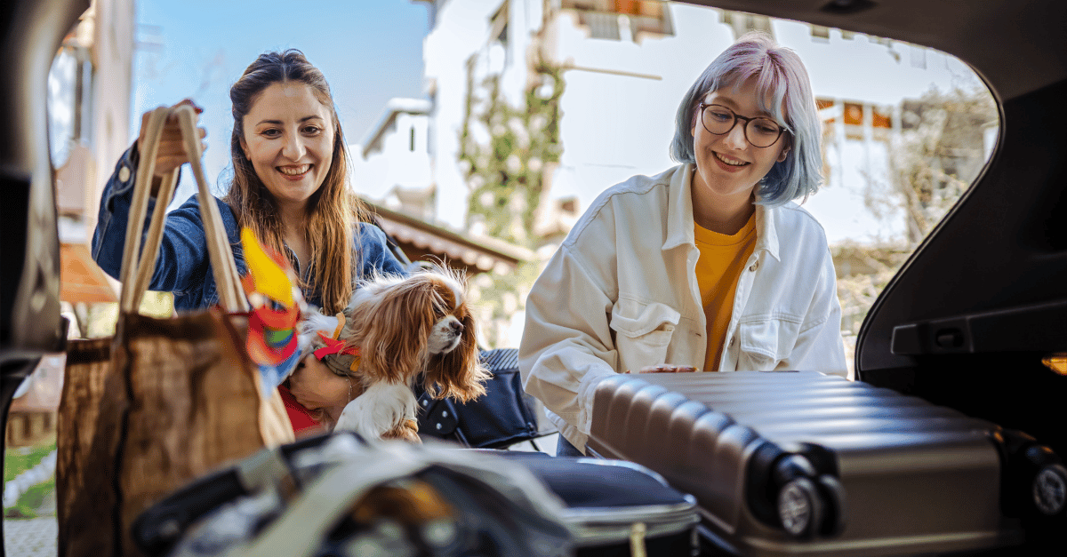 Two women packing their car up with luggage and reusable tote bags to be sustainable