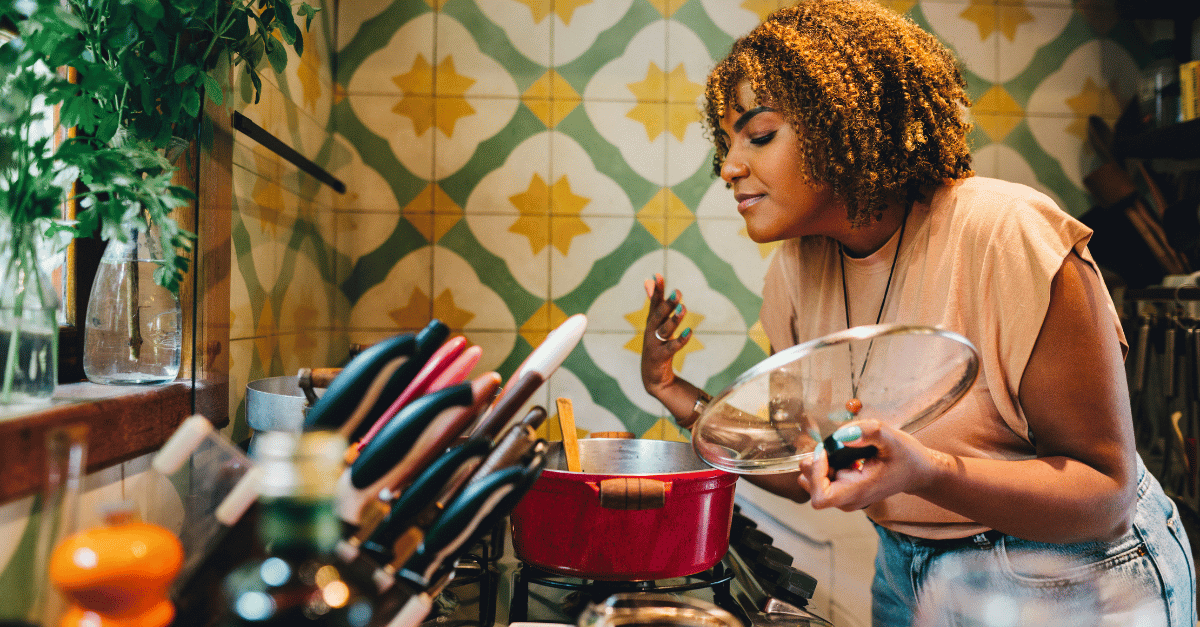 Woman cooking in her vibrant kitchen and loving the aroma from the pot